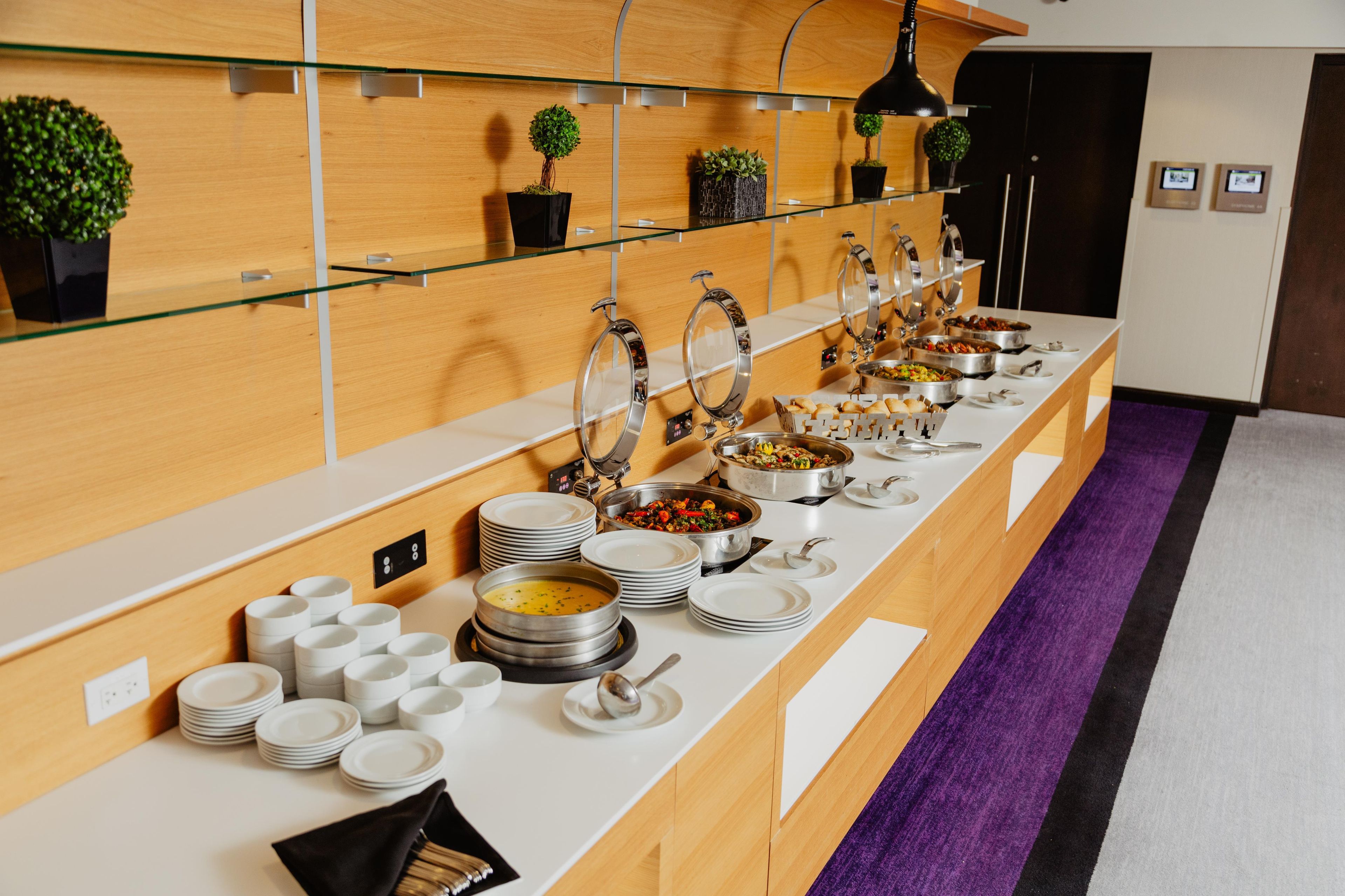 A buffet setup with multiple serving stations, including bowls of soup and various dishes, arranged on a long counter.