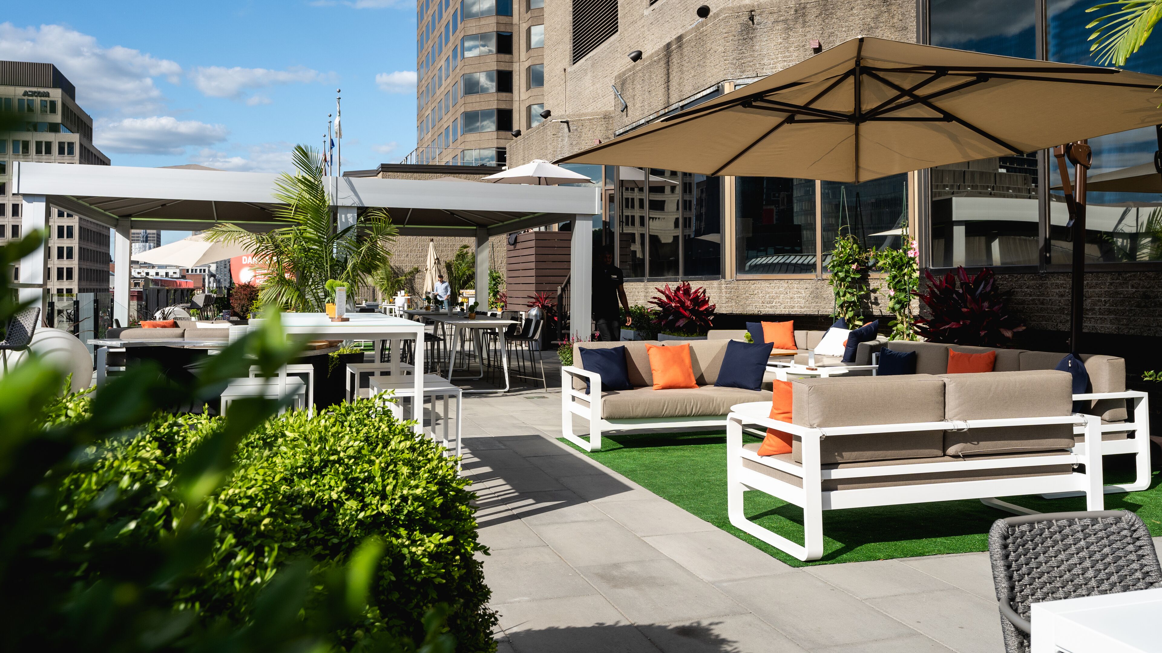 An outdoor seating area with white furniture, including sofas and chairs, under large umbrellas.