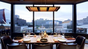 A dining area with a city view, large windows, and modern furniture. - DoubleTree by Hilton Montreal (Montreal)
