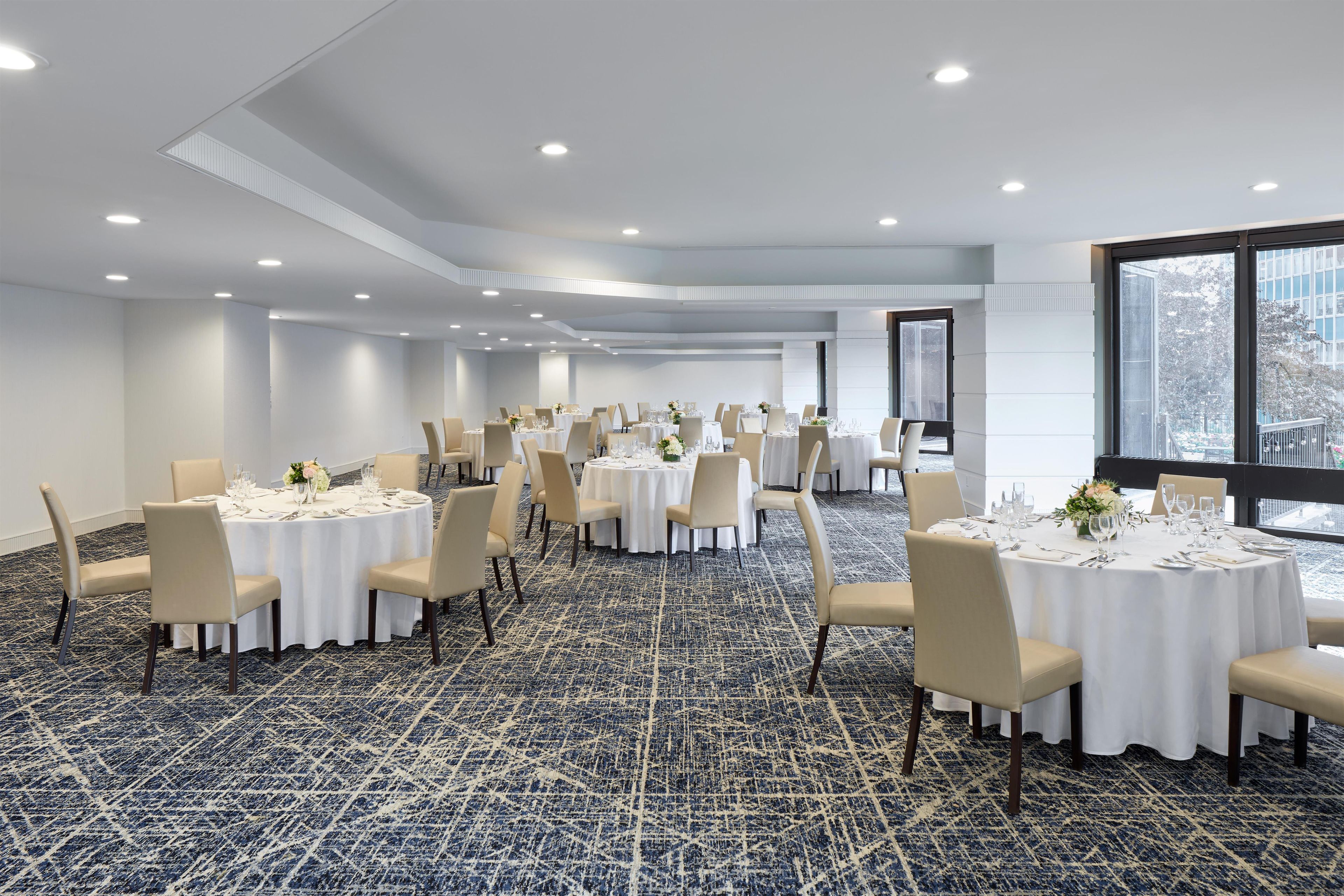 A conference room with round tables, chairs, and a carpeted floor.