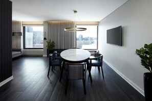 A modern dining area with a round table, dark wood flooring, and a city view through large windows. - DoubleTree by Hilton Montreal (Montreal)