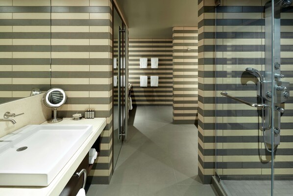 Un baño moderno con un lavamanos grande, espejo y ducha.