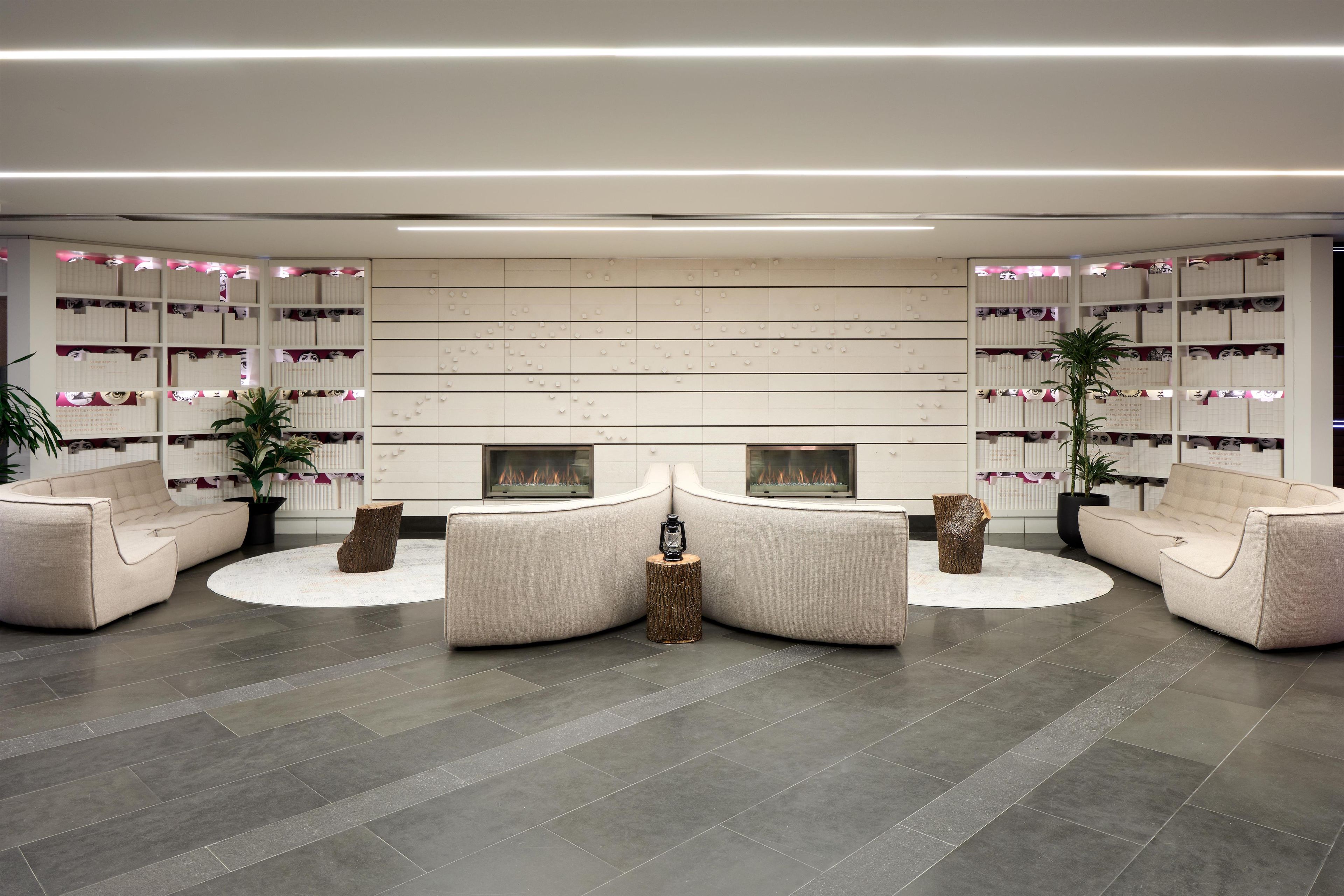 Un hall d’entrée moderne avec une cheminée, des canapés et une bibliothèque.