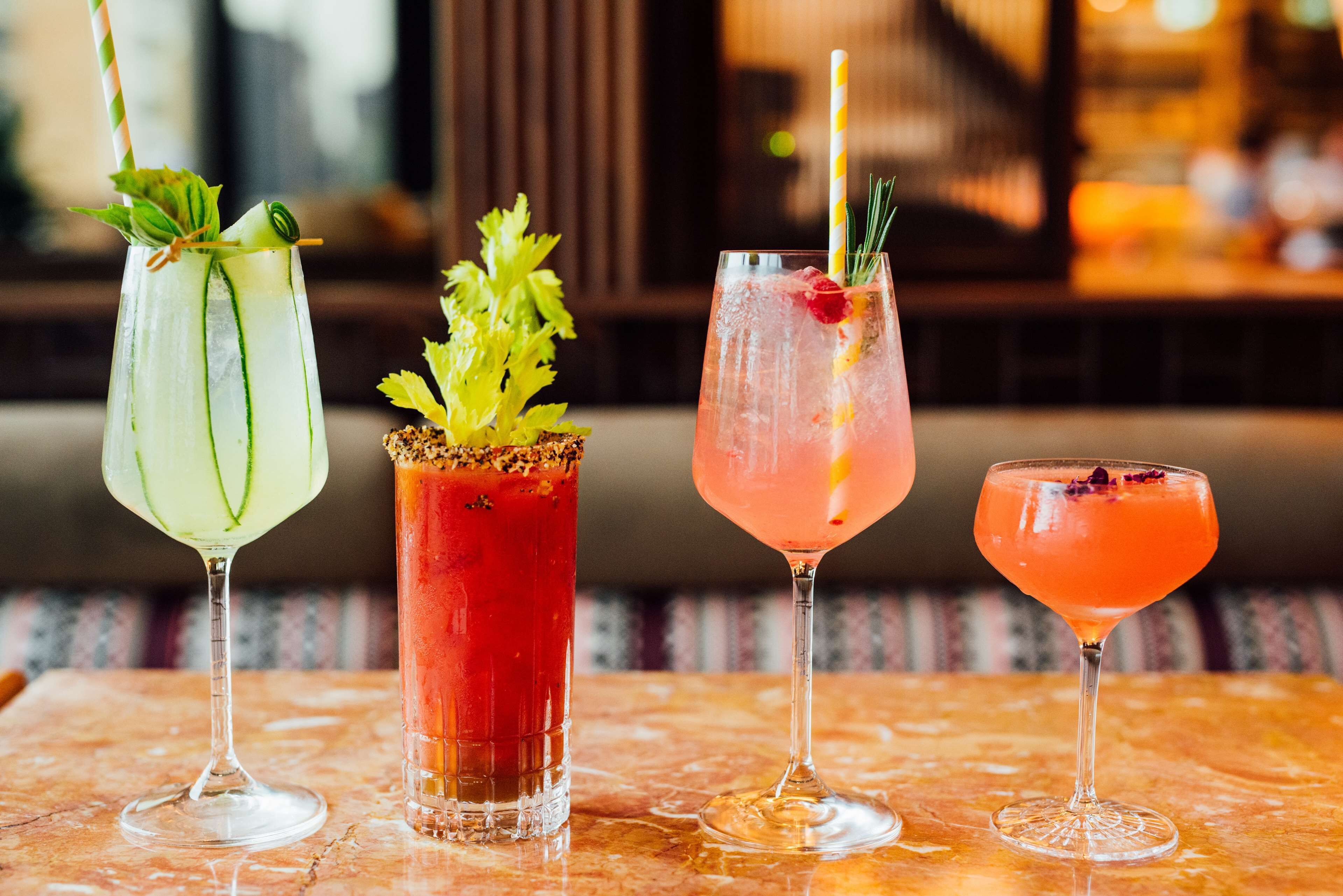 Four cocktails on a marble table with a blurred background.