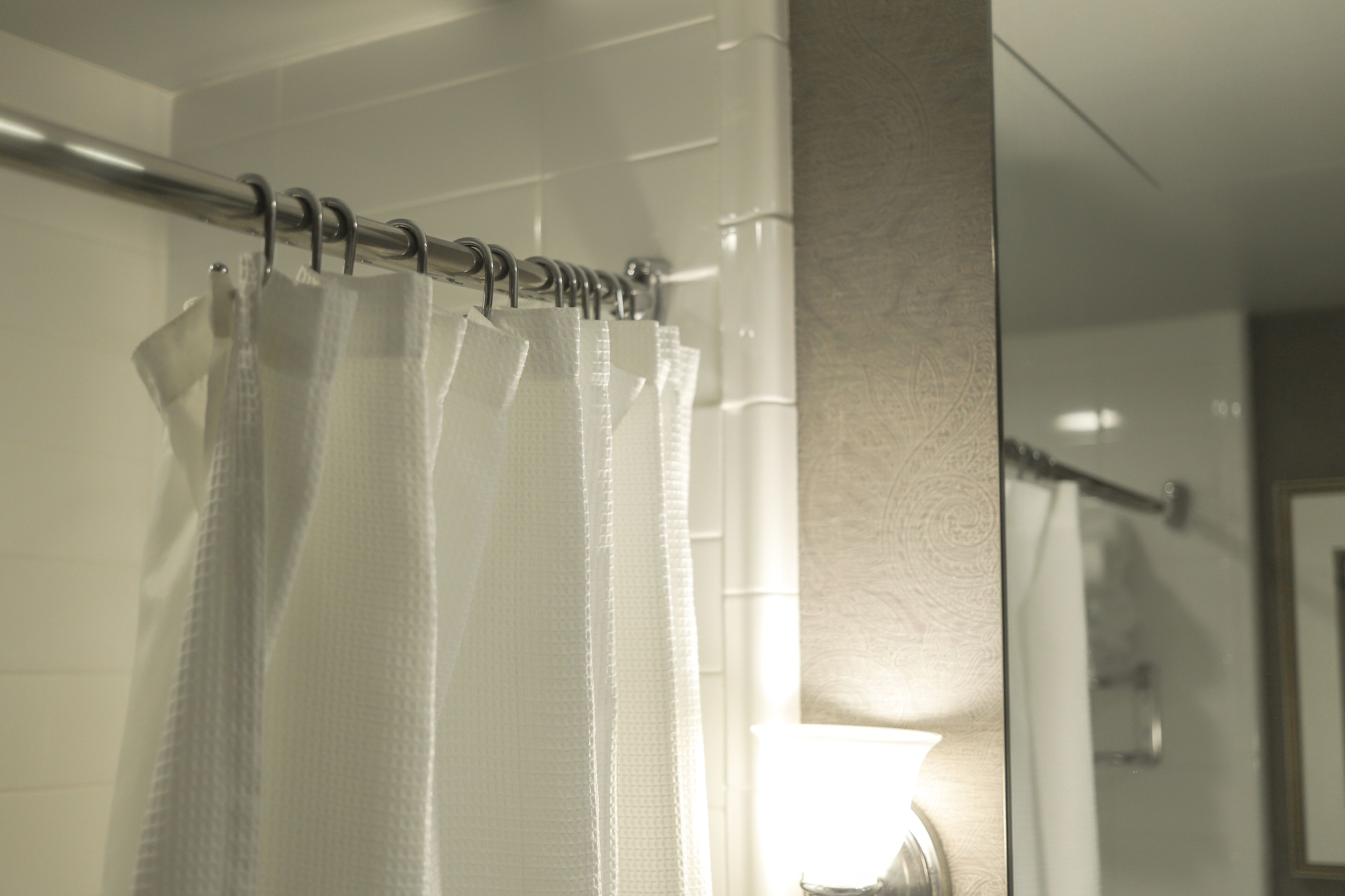 A bathroom with a shower curtain, a towel rack, and a mirror.