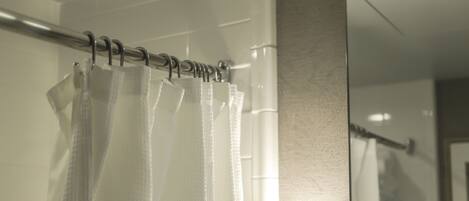 A bathroom with a shower curtain, a towel rack, and a mirror.