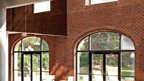 A swimming pool with clear blue water, surrounded by a brick wall and large arched windows. - Delta Hotels by Marriott Bessborough (Saskatoon)