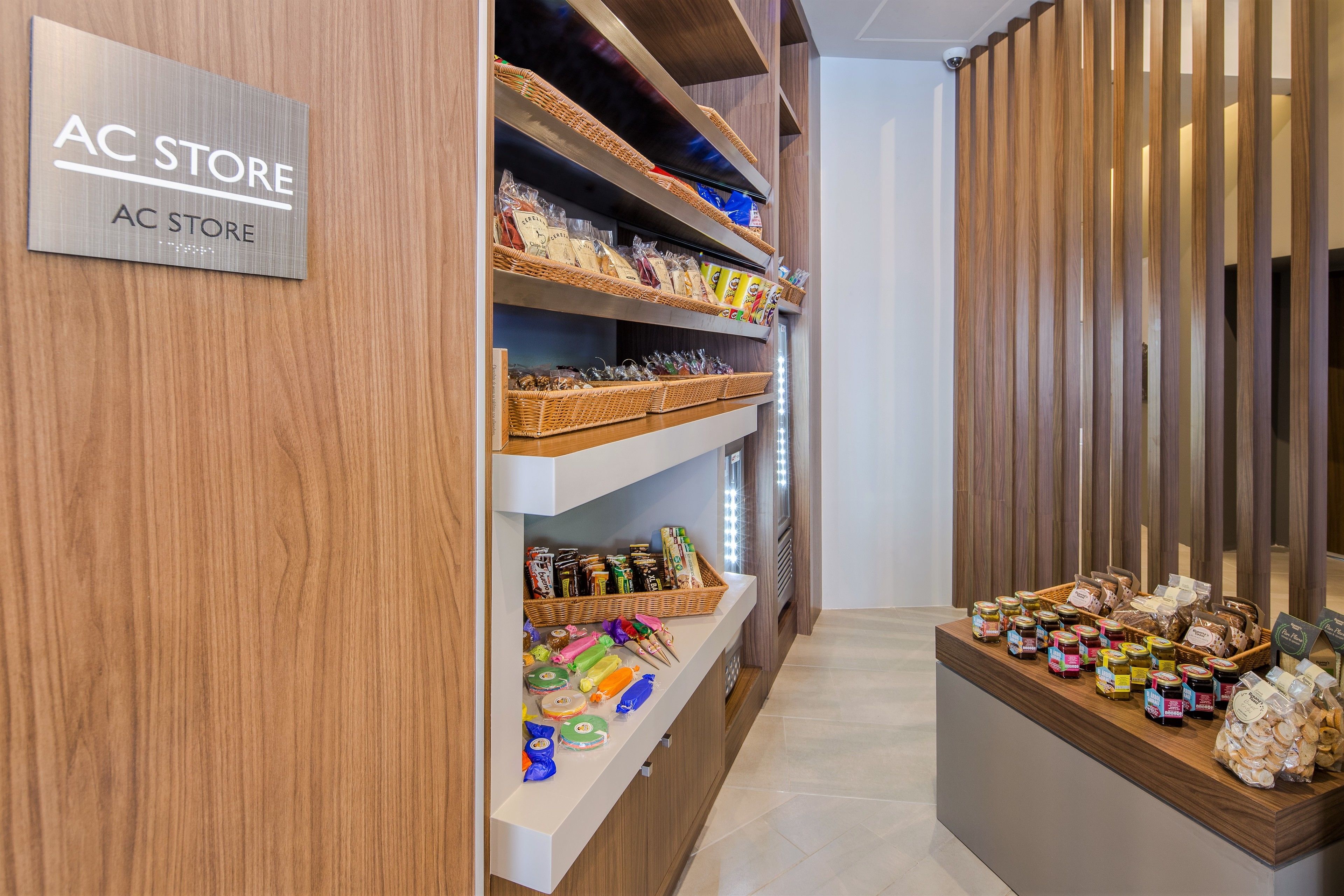 A store interior with wooden shelves stocked with various food items and a sign reading "AC STORE".