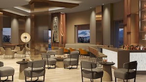 Un espace lounge moderne, doté de sièges, d’un bar et d’une grande fenêtre offrant une vue panoramique.