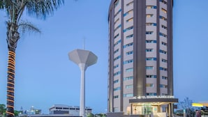 Un grand hôtel au design moderne, caractérisé par une entrée imposante et une vaste structure géométrique blanche située à proximité.