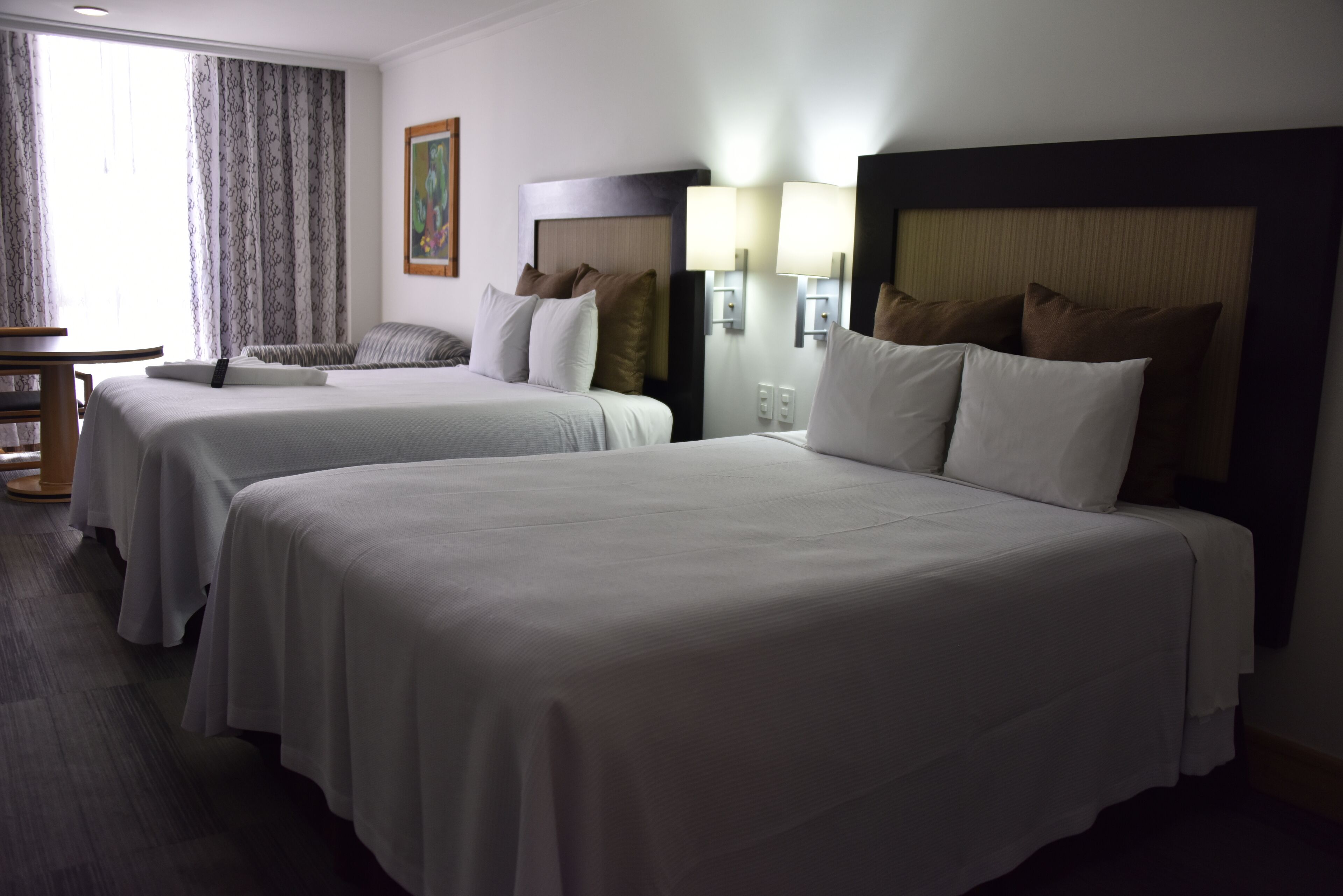 A hotel room with two beds, a desk, and a chair.