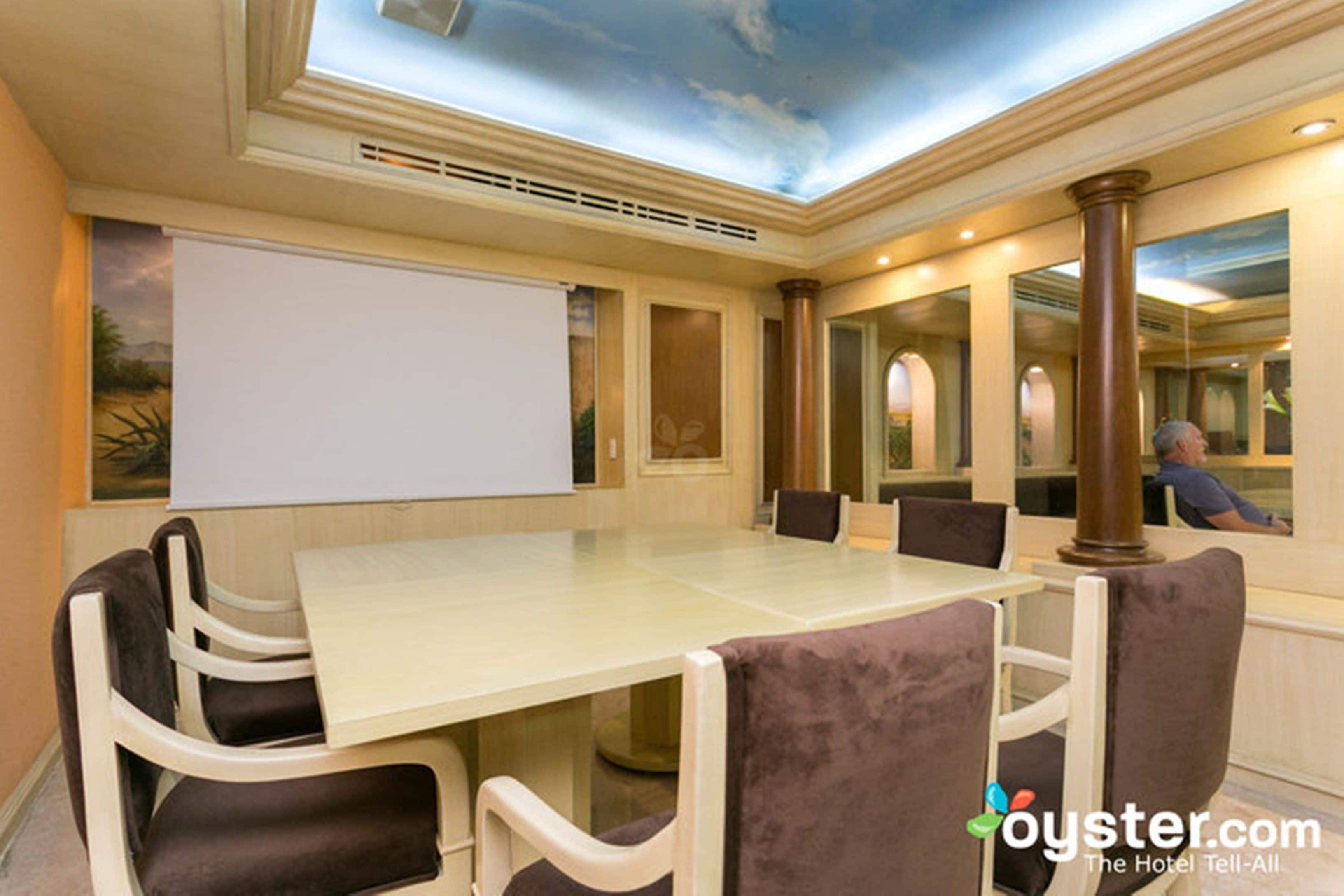 Een vergaderruimte met een grote tafel, stoelen, een whiteboard en een muurschildering aan het plafond.