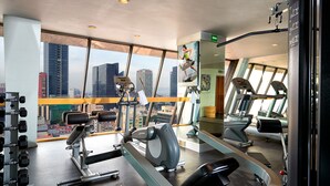 A gym with various exercise equipment, large windows, and a view of city buildings. - Hotel Royal Reforma (Mexico City)