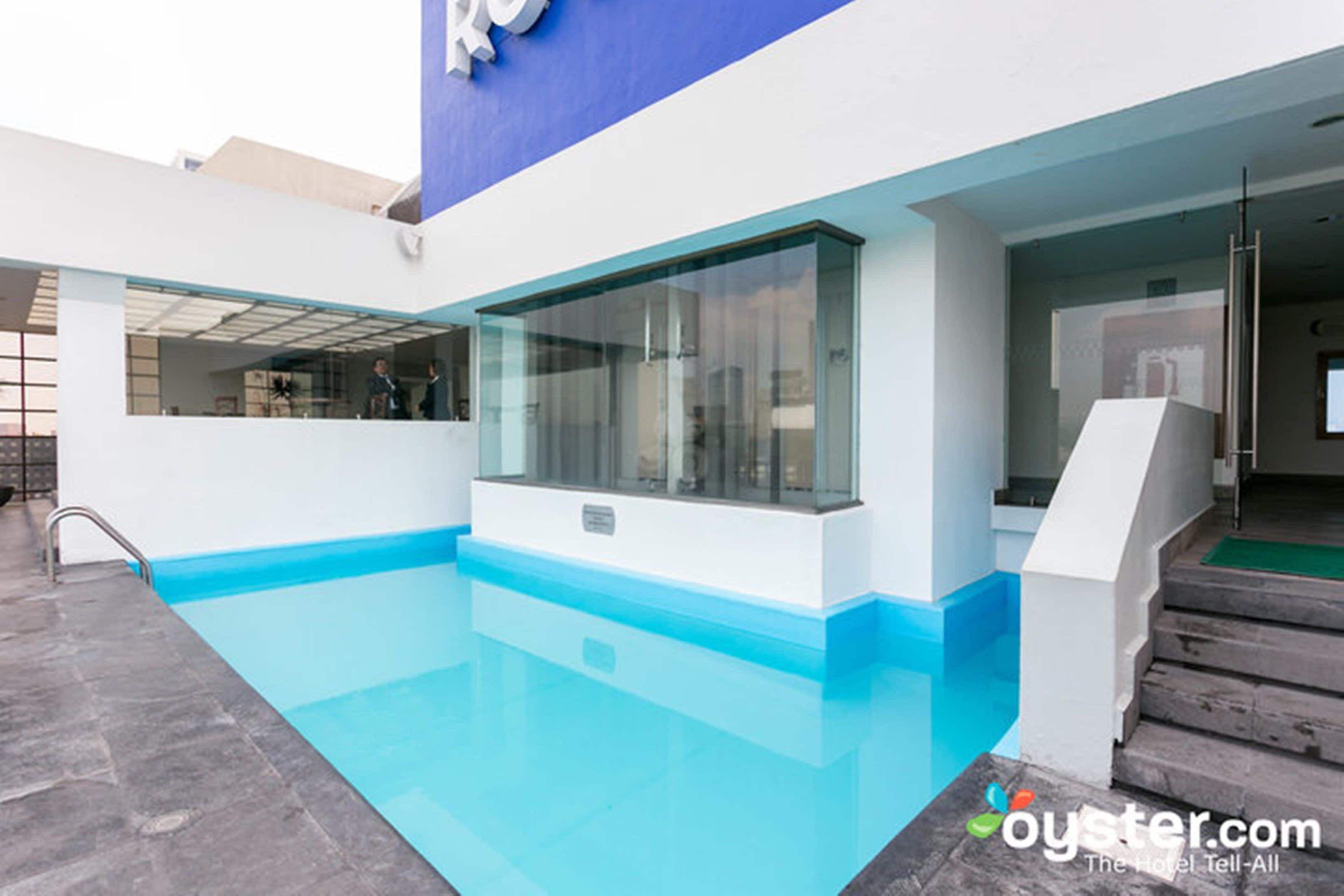 A modern hotel with a swimming pool, glass doors, and a staircase leading to the entrance.