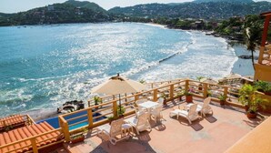 A seaside terrace with outdoor seating, a pool, and a view of the beach and ocean. - Hotel Irma (Zihuatanejo)