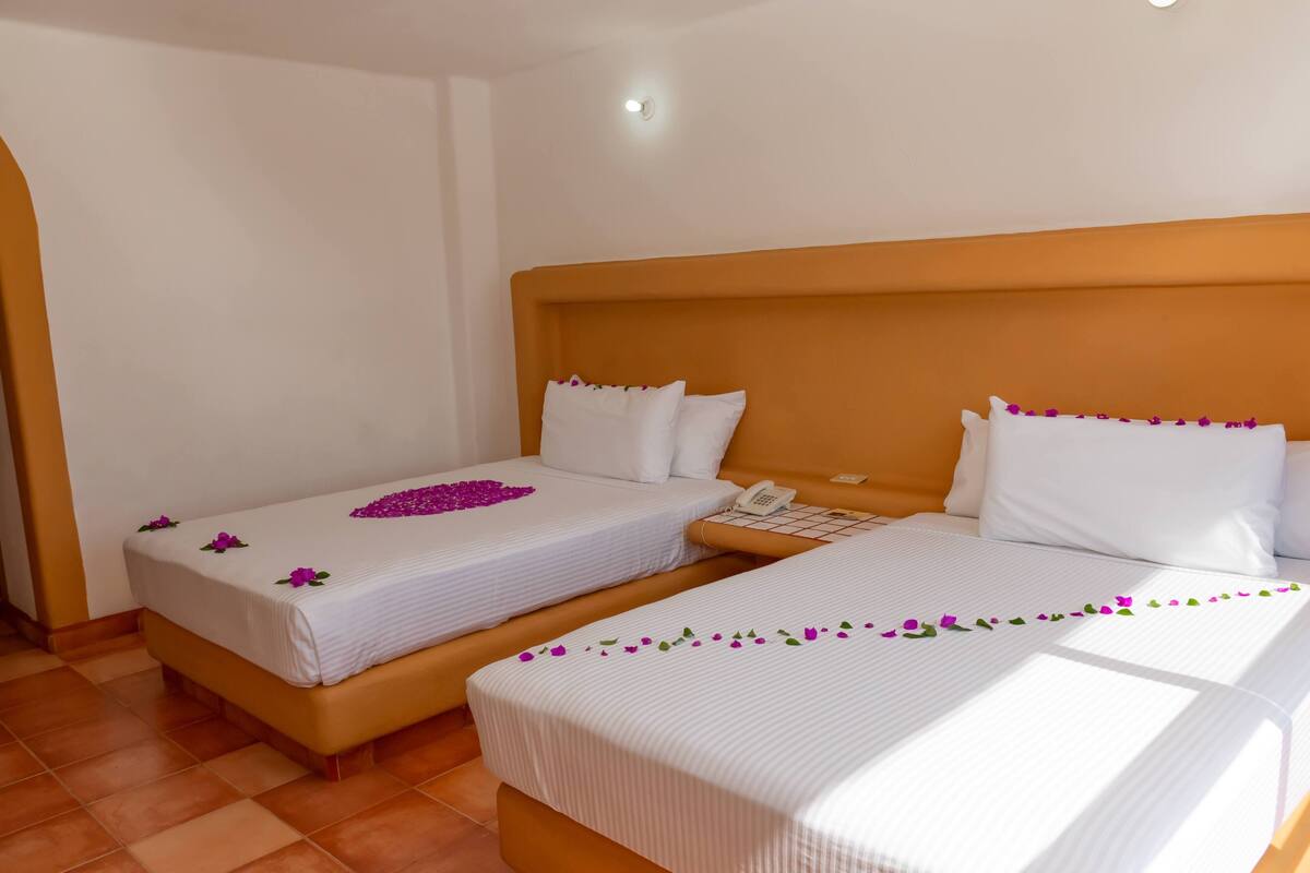Two single beds with white linens, a wooden headboard, and a bedside phone.