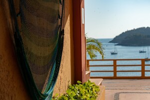 Varanda com vista para o mar, uma rede e uma pequena planta.