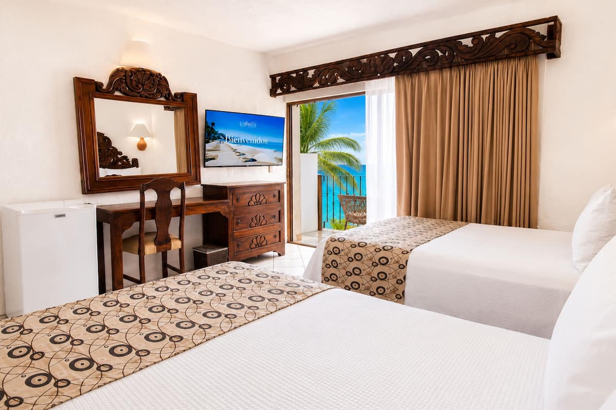 Une chambre d’hôtel avec deux lits, un bureau, une chaise, une télévision et une vue sur l’océan.