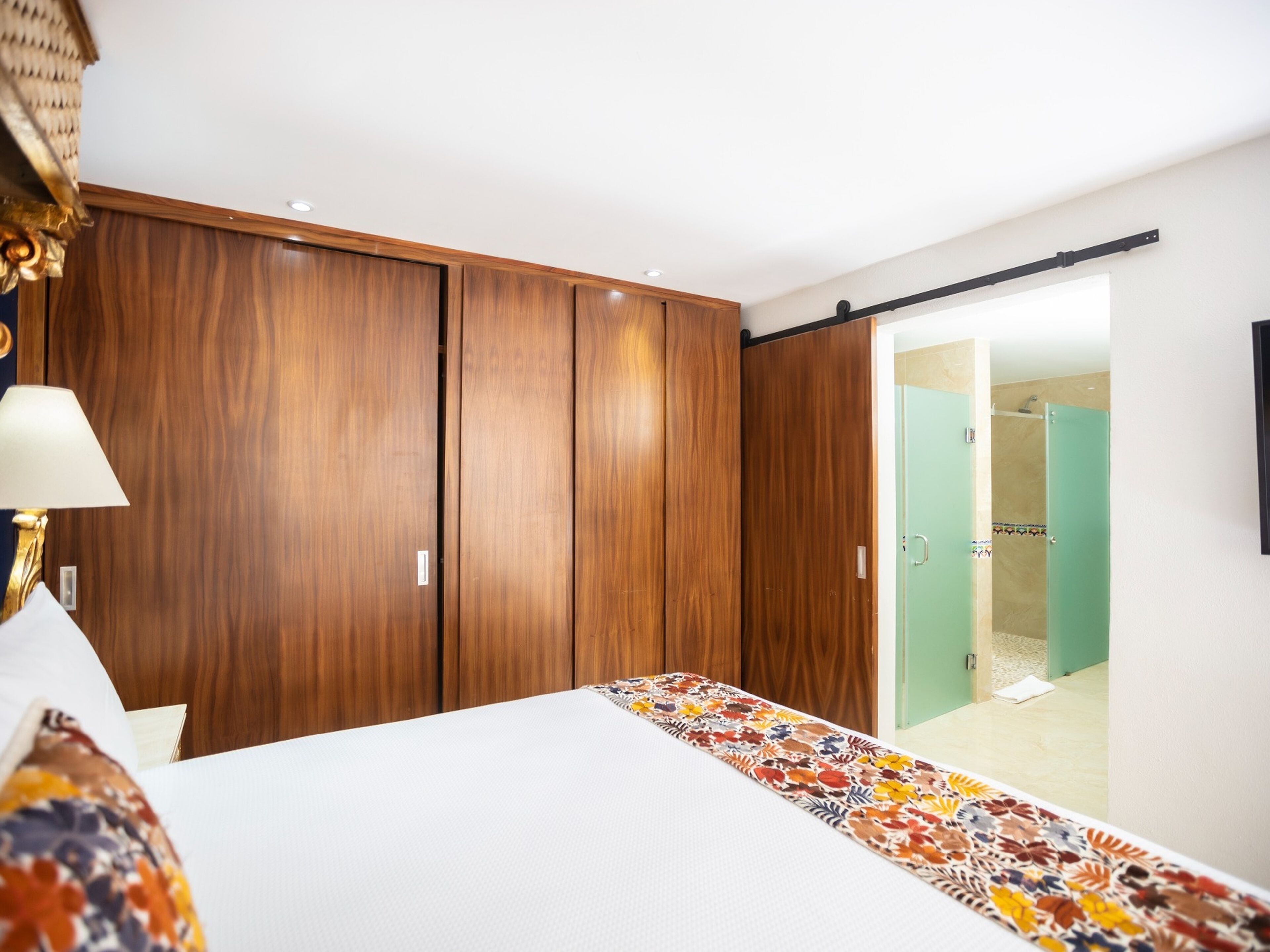 Une chambre à coucher comprenant un lit, une armoire, une salle de bain avec douche et une porte donnant sur une autre pièce.