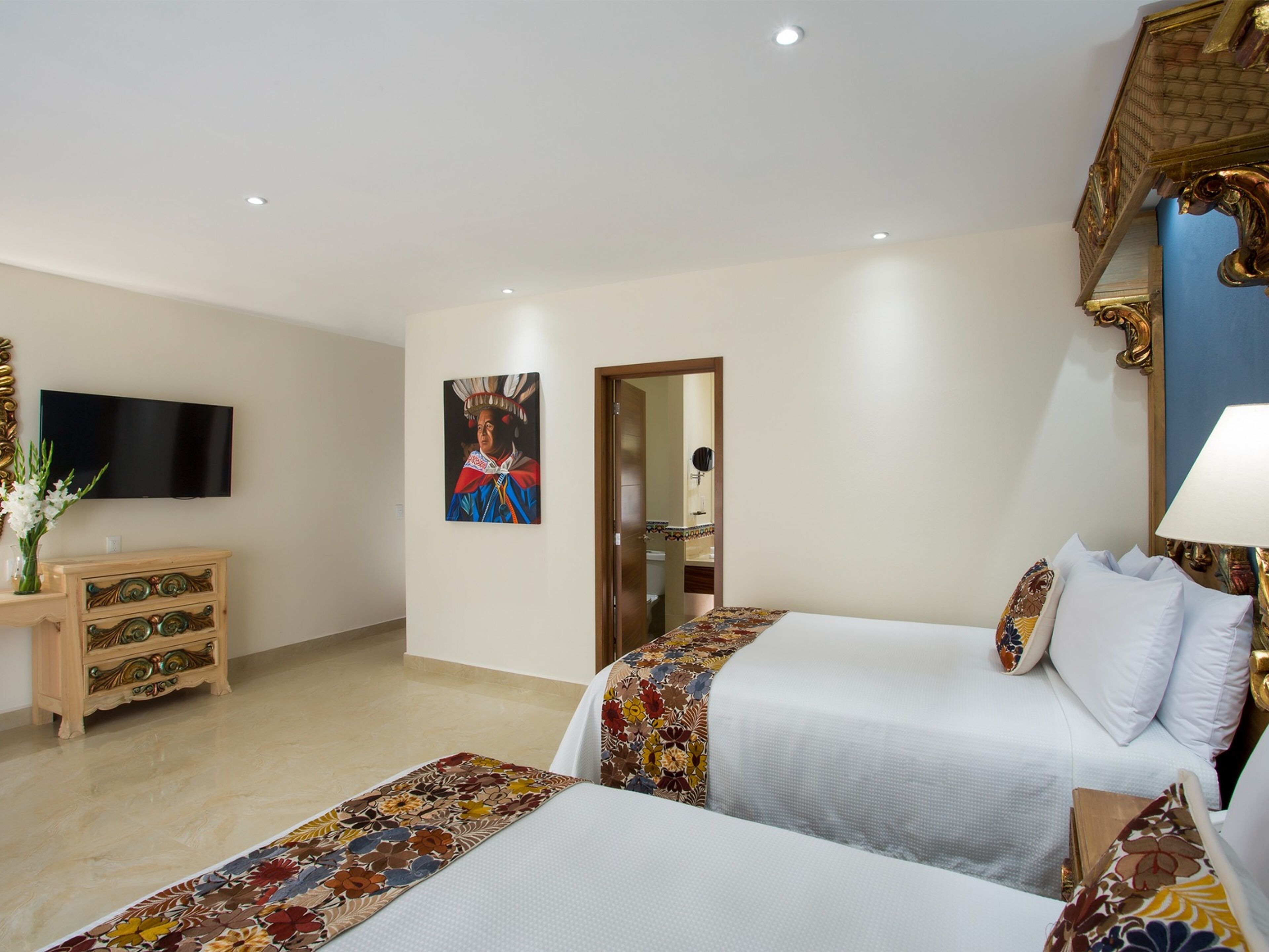 Une chambre d’hôtel avec deux lits, une télévision, une commode et un tableau au mur.