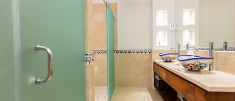 A bathroom with a shower, a sink with a decorative bowl, a mirror, and a towel rack.