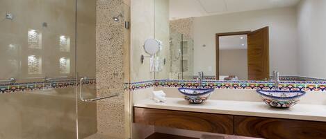 A modern bathroom with a glass-enclosed shower, two vessel sinks, and a wooden vanity.