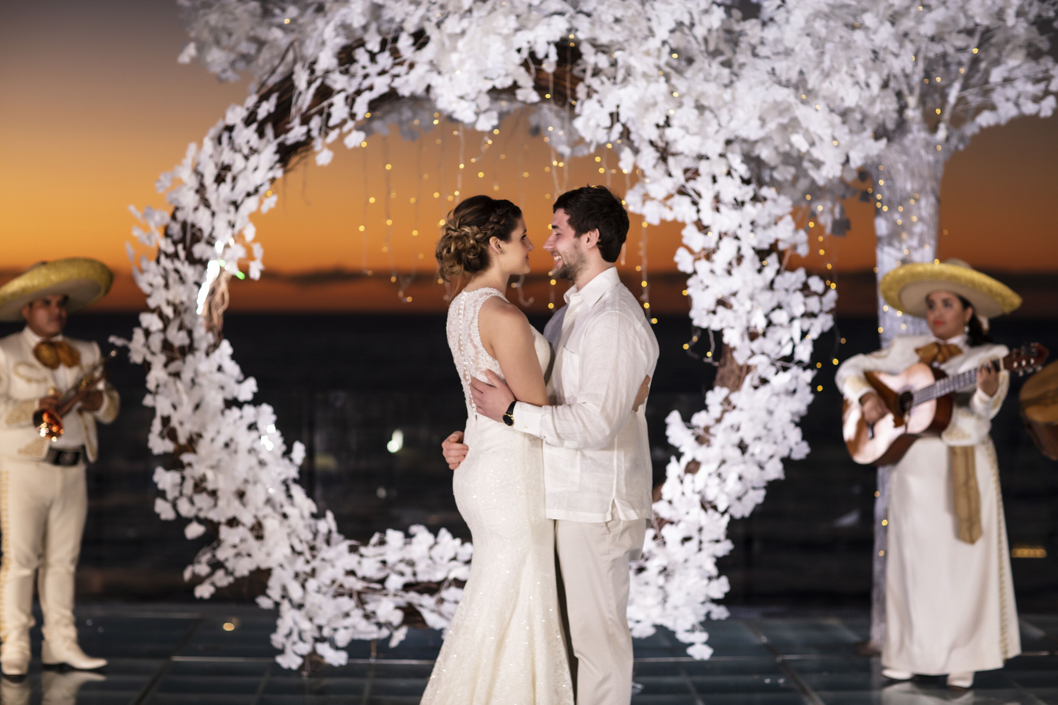 Cerimônia de casamento com um arco de flores e músicos.
