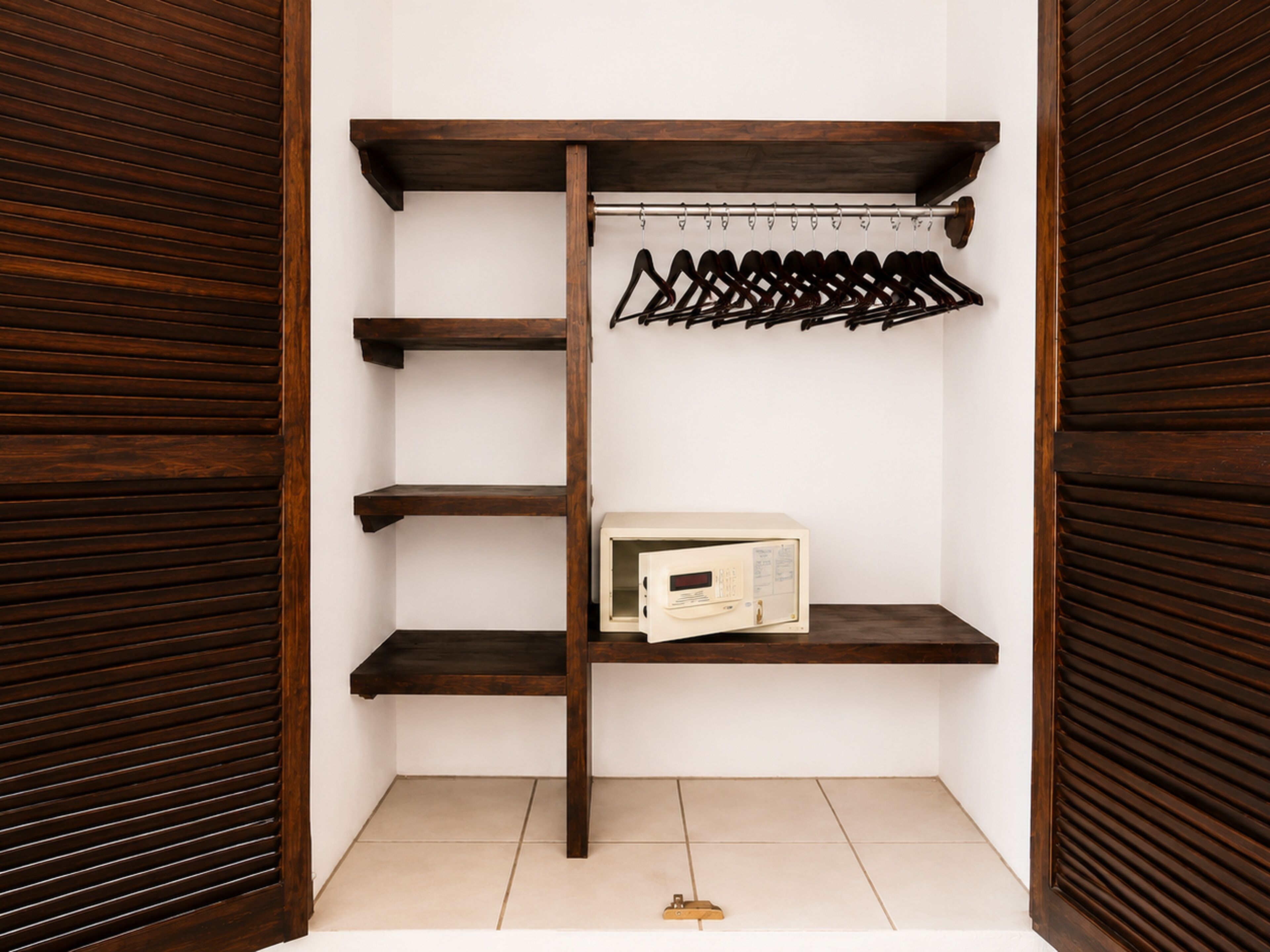 A closet with wooden shelves, a hanging rack, and a microwave.