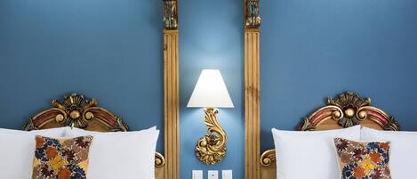 Een hotelkamer met twee bedden, een nachtkastje met een lamp en een telefoon.
