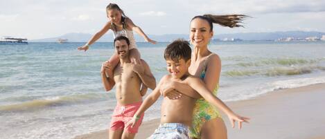 A beach scene with a group of people enjoying the water.