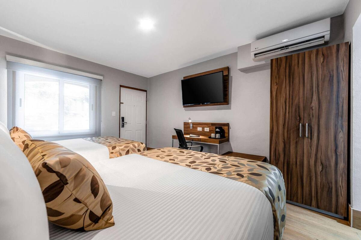 A hotel room with two beds, a desk, a television, and a wardrobe.