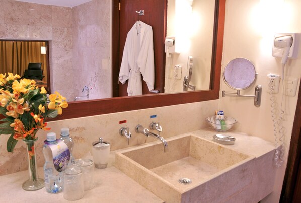 A bathroom with a sink, mirror, robe, and toiletries. - Hotel Terranova (Coatzacoalcos)