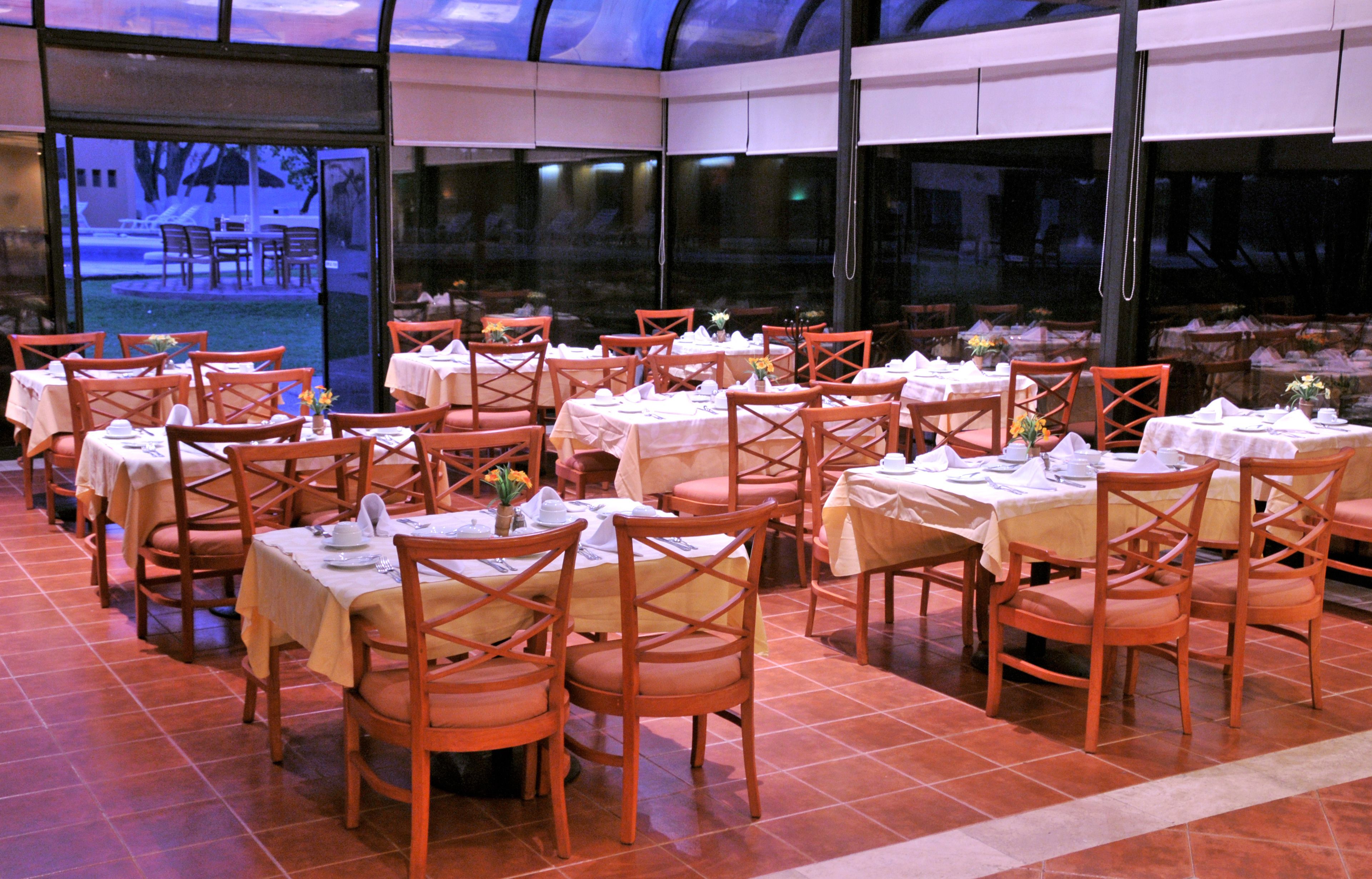 A restaurant with multiple tables and chairs, arranged in a spacious indoor setting with large windows.
