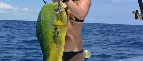 A person holding a large fish on a boat.