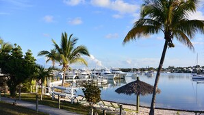A marina with boats docked, palm trees, and a thatched-roof structure. - Green Turtle Club Resort & Marina (Green Turtle Cay)