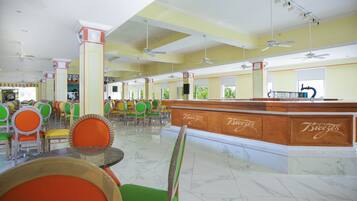 Um restaurante amplo com pé direito alto, várias ventoinhas no teto e um balcão central com o nome 'Breeze'.