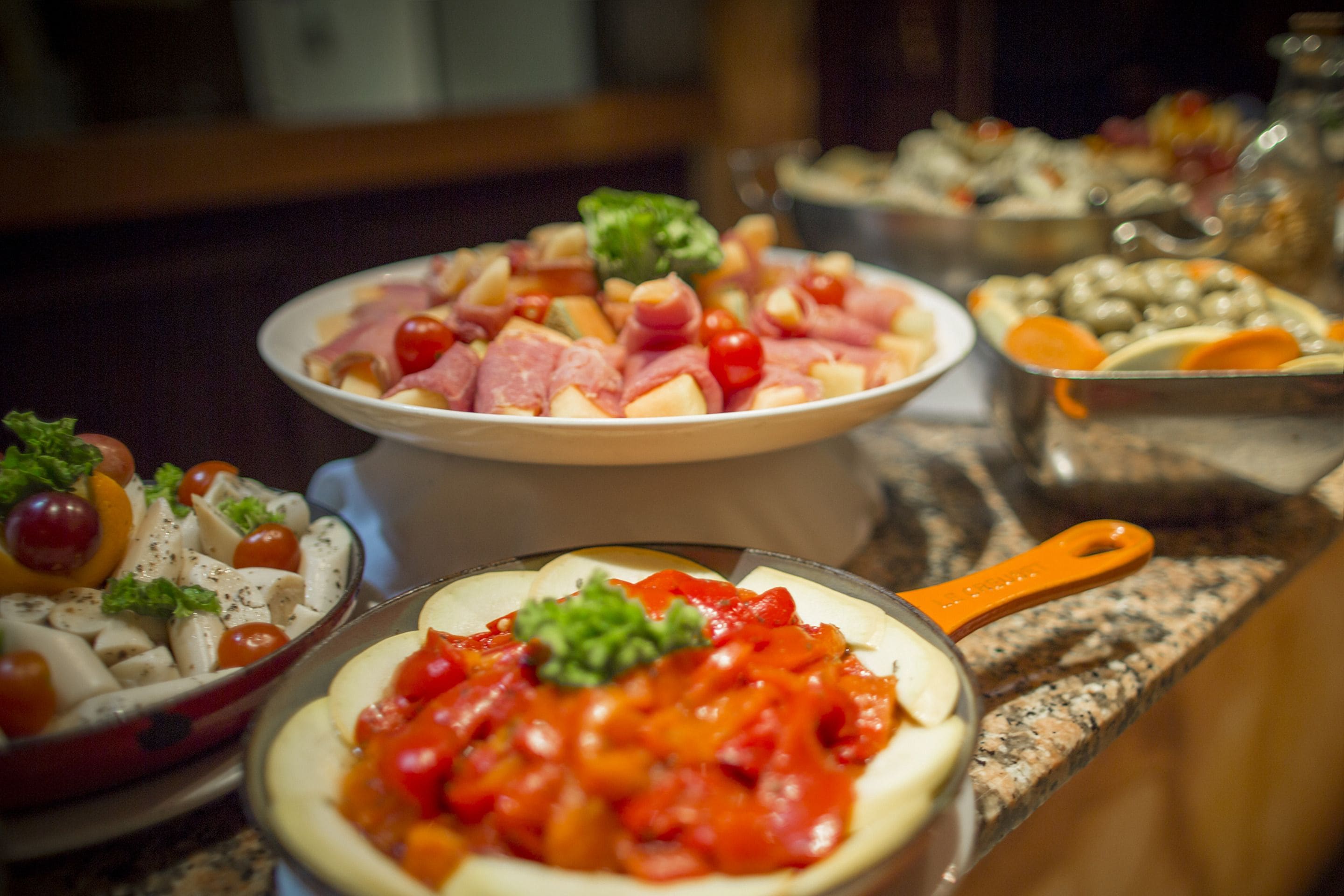 A buffet with various dishes including pasta, vegetables, and meats.