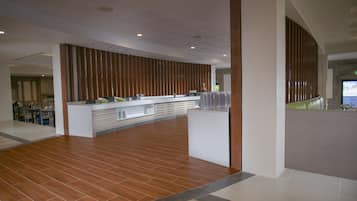 Een moderne lobby met een receptiebalie, houten lambrisering en een betegelde vloer.
