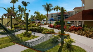 Un resort con piscina, palmeras y una hamaca.