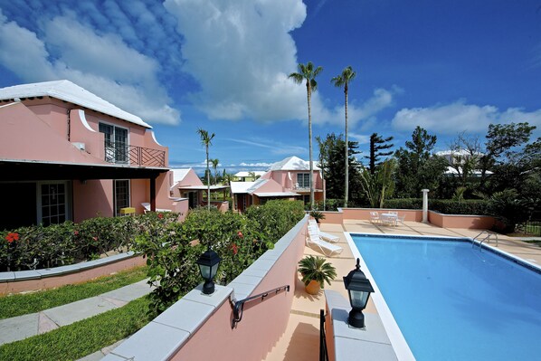 Una piscina al aire libre, sillones reclinables de piscina