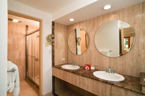 A bathroom with two sinks, a large mirror, and a glass shower enclosure.