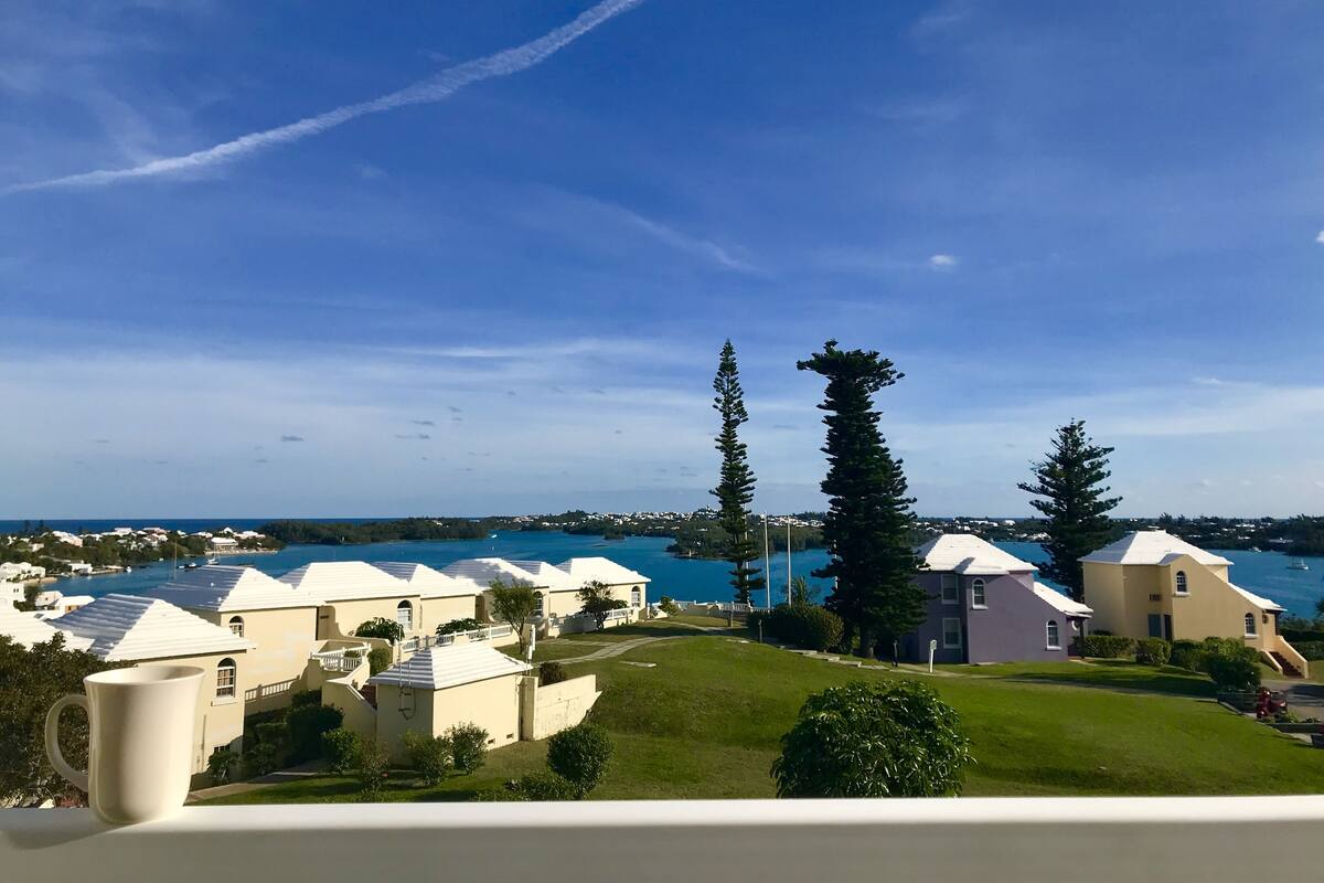 A coastal residential area with houses, a clear sky, and a view of the sea.