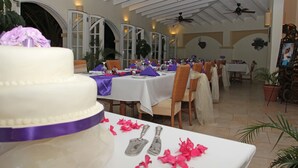 A banquet hall with white tables, purple tablecloths, and chairs. - Blue Horizons Garden Resort (St. George's)