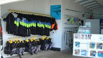 A room with a wall-mounted rack of diving gear, a shelf with books, and a poster.