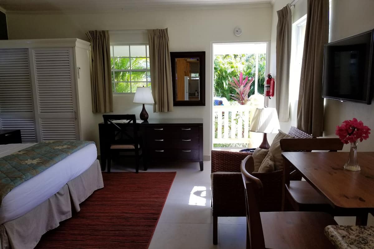 Habitación de hotel con cama, escritorio, silla y una mesa de comedor con un florero.