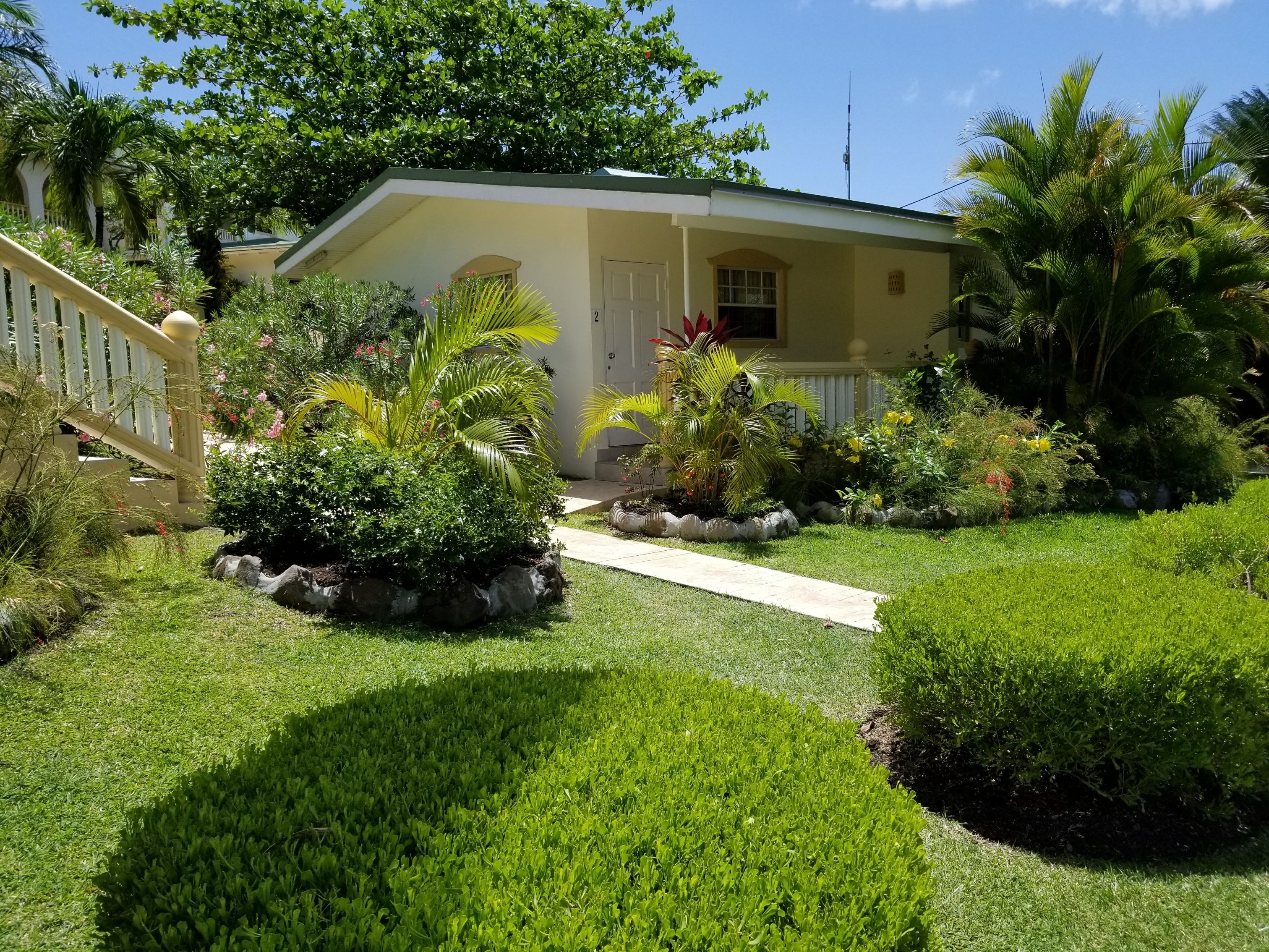 Una casa con un jardín cuidado, un sendero que lleva a la puerta principal y una valla blanca.