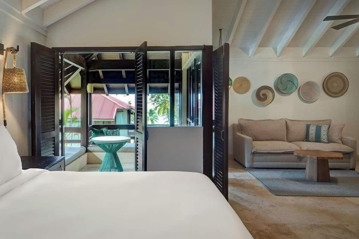 Un dormitorio con cama, ventana con contraventanas, vista al exterior, sofá y mesa de centro.