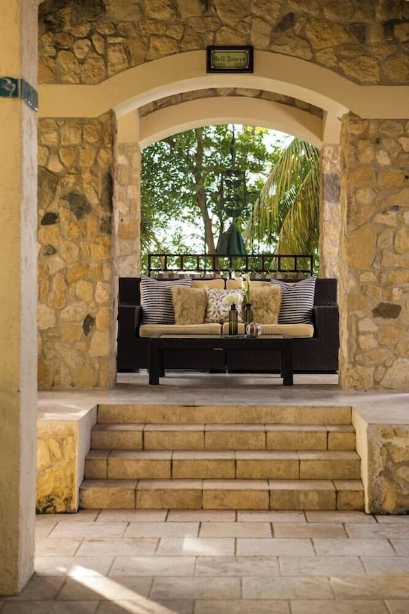 A stone-walled outdoor seating area with a bench, a coffee table, and a sign reading 'Bell Tower.'