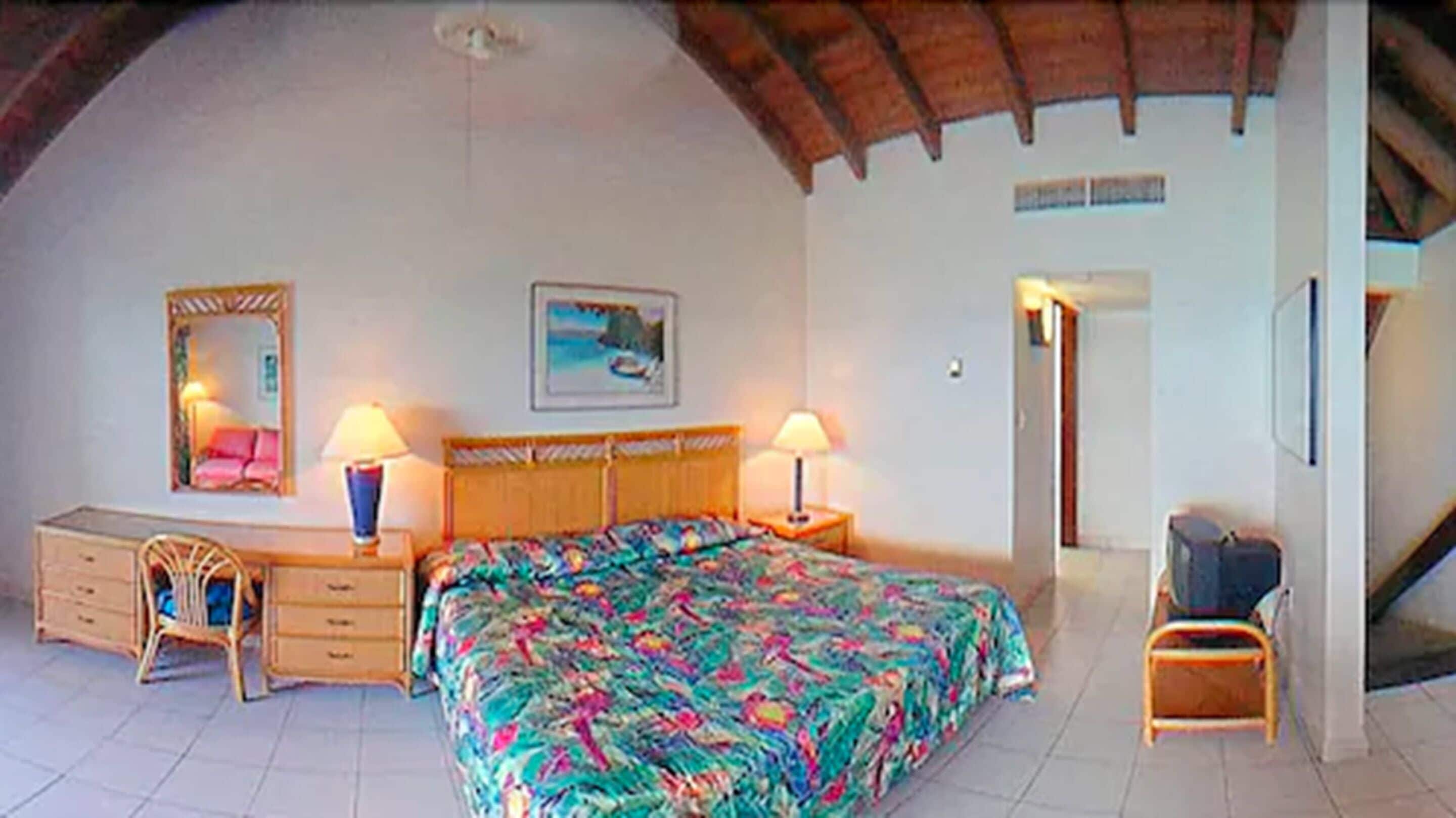 A bedroom with a bed, two bedside tables, a dresser, a chair, a mirror, and a painting on the wall.