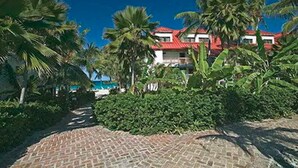 A resort with a red-roofed building surrounded by lush greenery and palm trees. - Sapphire Beach Resort (St. Thomas)